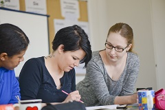 Drei Frauen sitzen an einem Tisch über Lernmaterialien